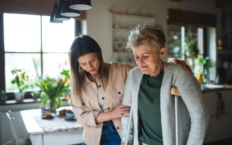 In-home caregiver helping woman into the home.
