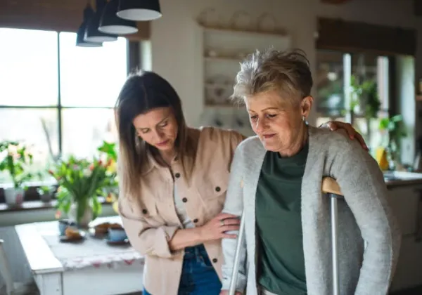 In-home caregiver helping woman into the home.