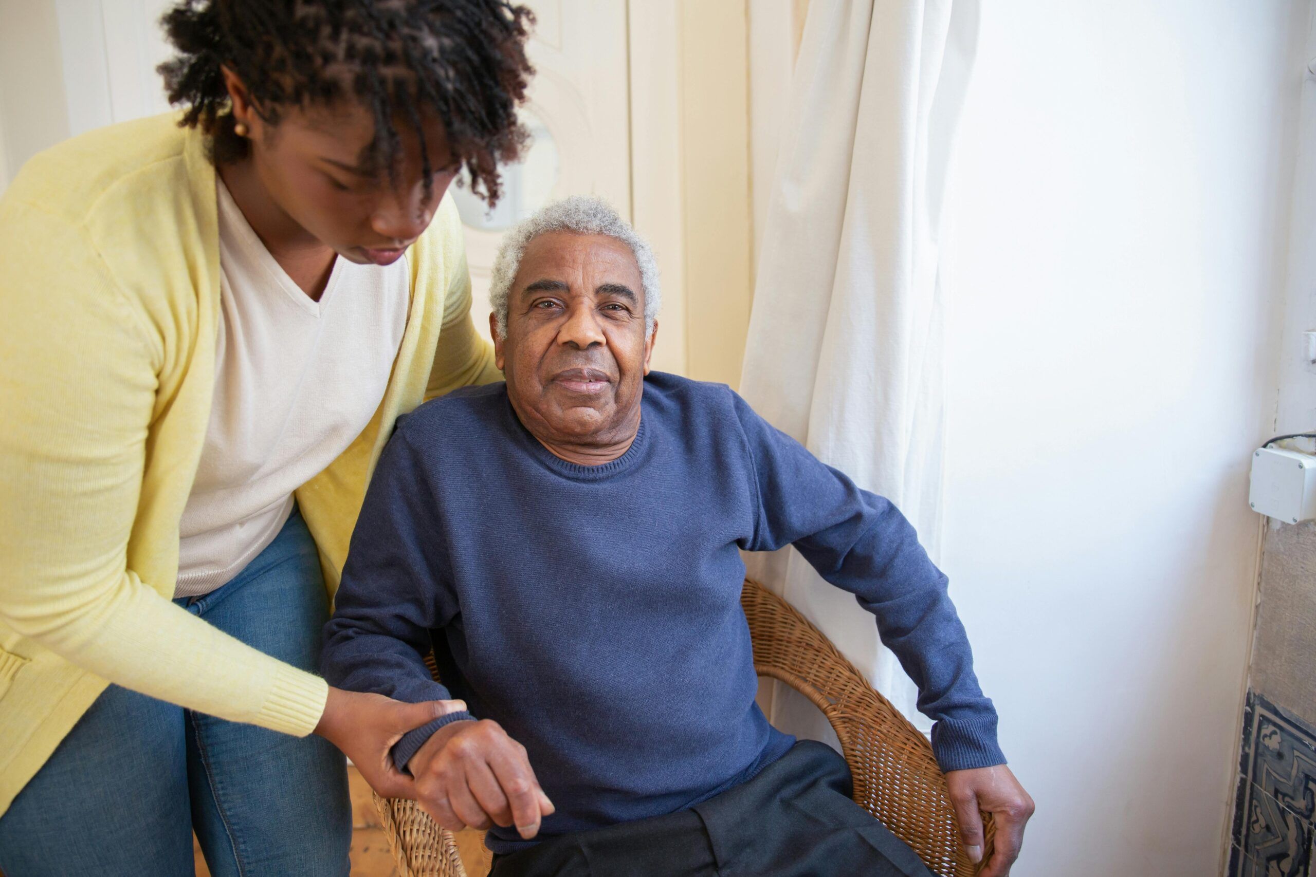 A caregiver helping elderly man up.